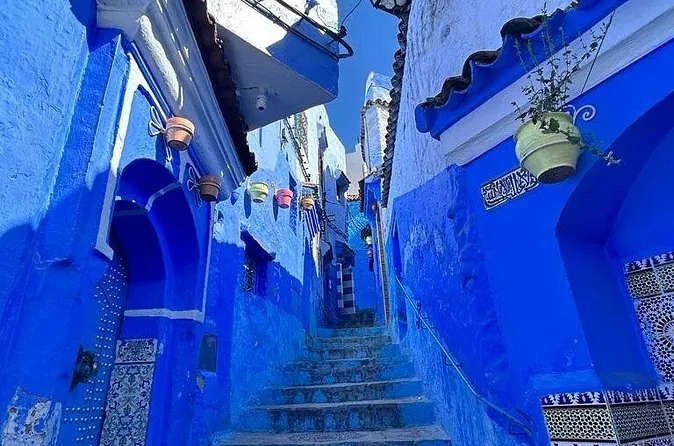 Un callejón escalonado de azul intenso con macetas colgantes en Chefchaouen