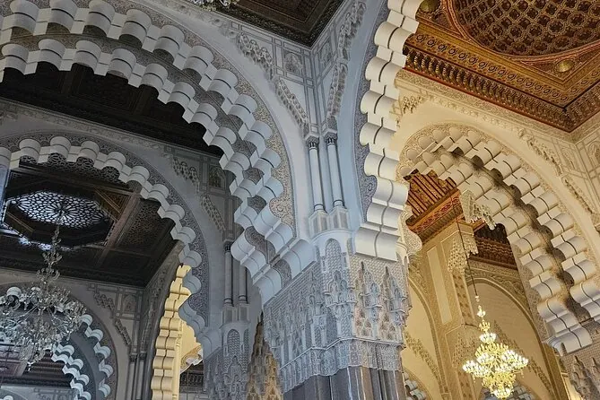 Arcos blancos tallados y una lámpara de araña en el interior de la Mezquita Hassan II