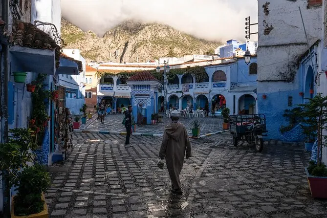 Una plaza empedrada en la medina de Chefchaouen con una montaña detrás